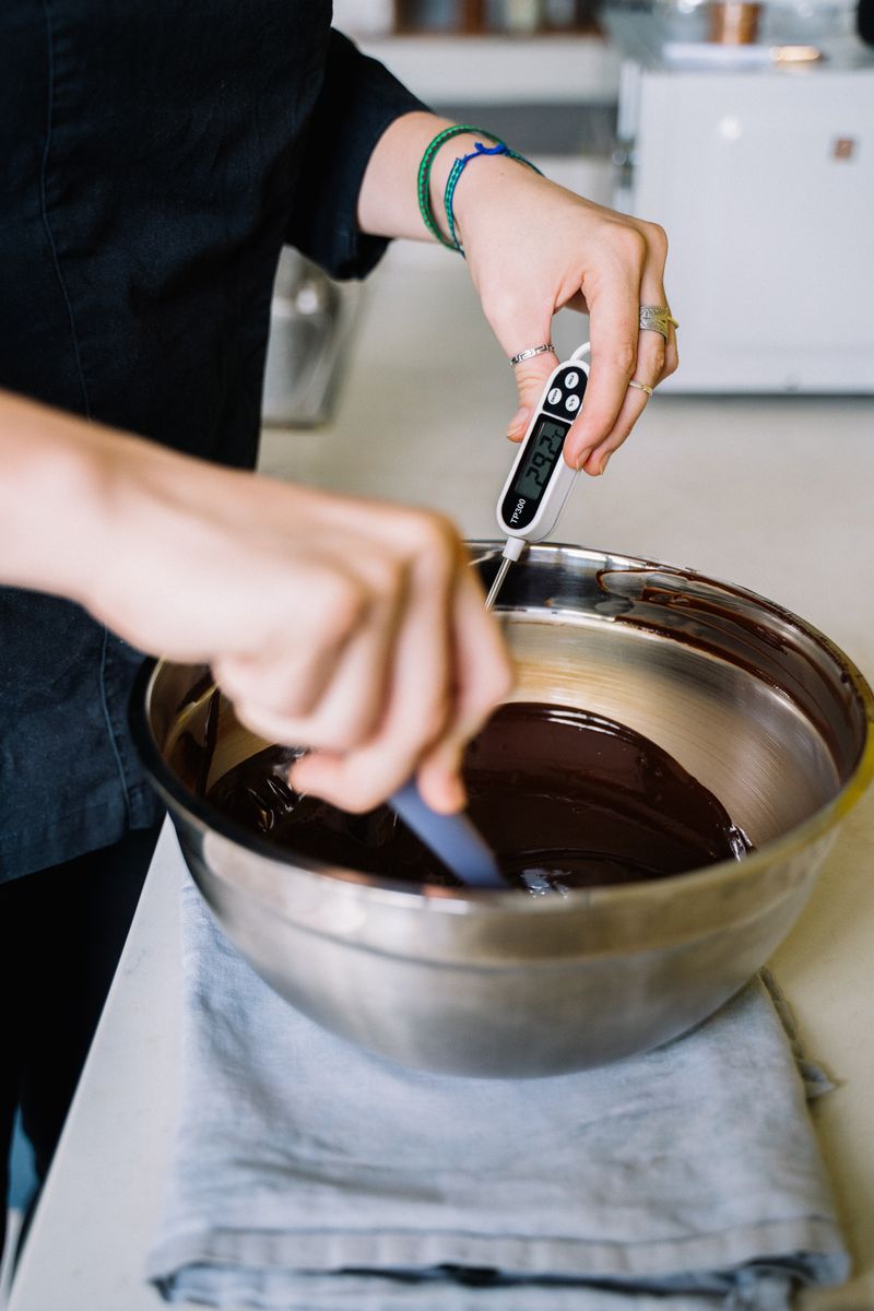 A confectioner hand-dipping chocolates in the kitchen